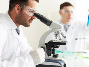 Two men in lab coats looking through a microscope.
