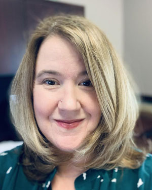 A woman in a green shirt smiles for the camera.